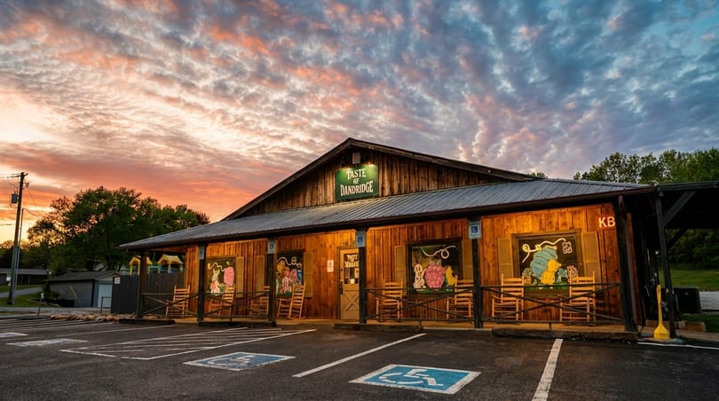 Taste of Dandridge restaurant, a rustic wooden building with a porch and rocking chairs, at sunset.